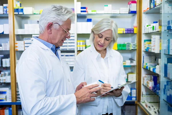 Farmacêuticos verificando e escrevendo prescrição de medicamentos — Fotografia de Stock