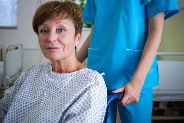 Portrait of patient sitting on wheel chair with nurse standing b — Stock Photo, Image