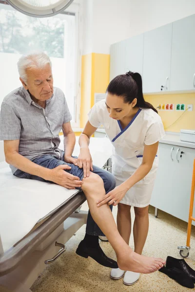 Female doctor examining patients knee — Stock Photo, Image