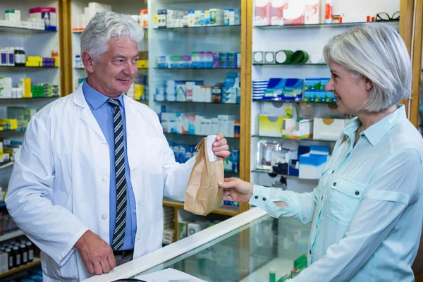 Farmacêutico dando pacote de medicamento ao cliente — Fotografia de Stock