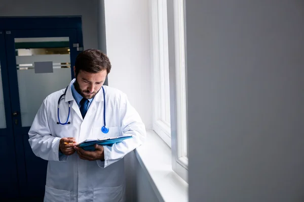 Doctor en pasillo mirando el portapapeles — Foto de Stock