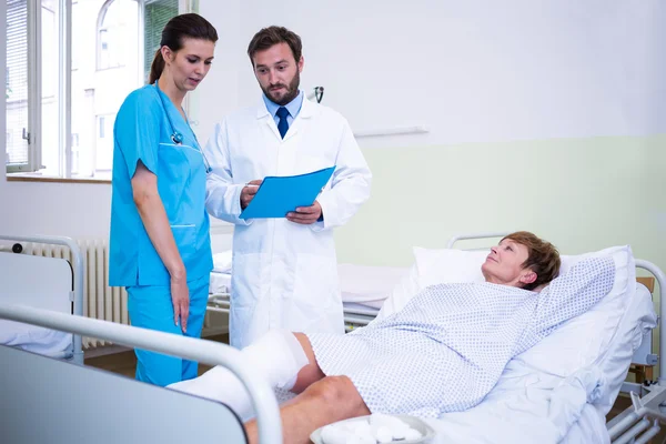 Médico y enfermera discutiendo sobre la pierna del paciente — Foto de Stock