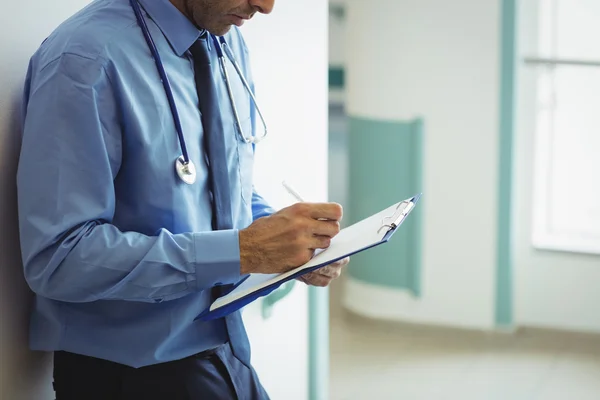 Seção intermediária do médico escrevendo na área de transferência — Fotografia de Stock