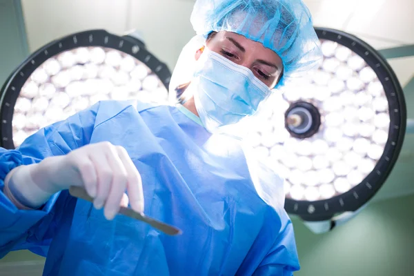 Γυναίκα χειρουργό κρατώντας ιατρικό εξοπλισμό στο χειρουργείο — Φωτογραφία Αρχείου