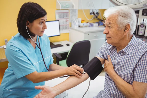 Médica verificando a pressão arterial do paciente — Fotografia de Stock