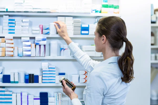 Farmacéutico revisando medicamentos en estante — Foto de Stock