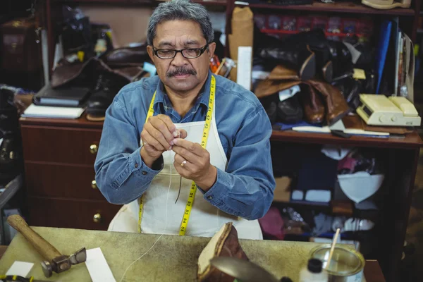 Shoemaker putting thread in the needle — Stock Photo, Image
