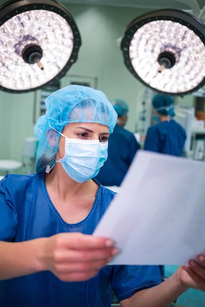Chirurgin liest Bericht im Operationssaal — Stockfoto