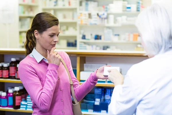 Pharmacist assisting box of medicine to customer — Stock Photo, Image