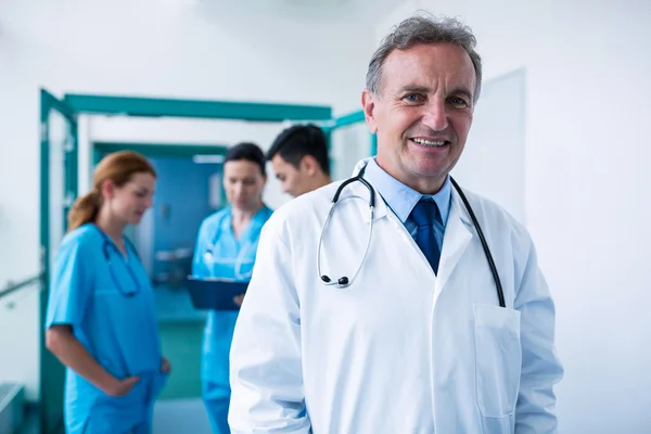 Medico sorridente in piedi in corridoio — Foto Stock