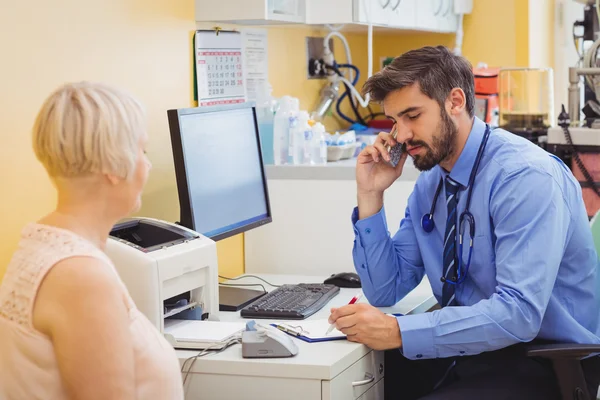 Médico na mesa falando por telefone — Fotografia de Stock