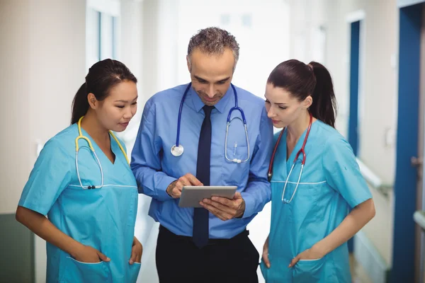 Médico e enfermeiros discutindo sobre tablet — Fotografia de Stock