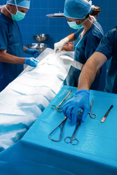 Хирург забирает ножницы из подноса — стоковое фото