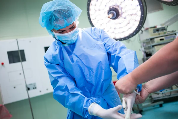 Nurse helping a surgeon in wearing surgical gloves — Stock Photo, Image
