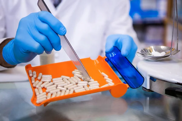 Farmacêutico colocando pílulas em recipiente — Fotografia de Stock