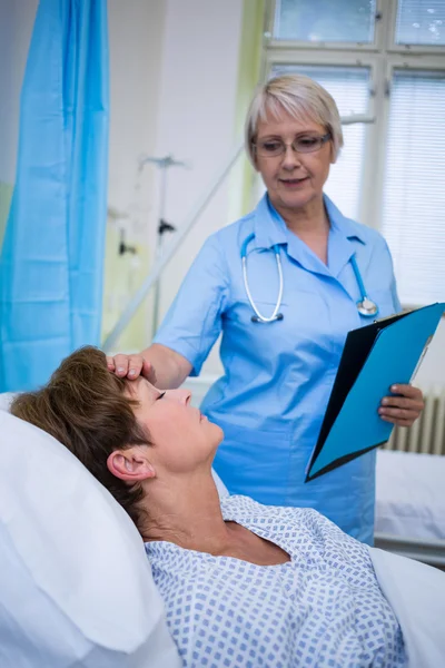 Verpleegster die zijn patiënt temperatuur controleren — Stockfoto