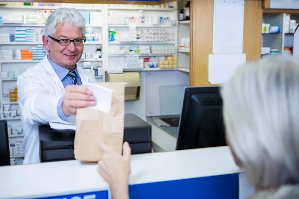 Farmacêutico dando pacote de medicamento ao cliente — Fotografia de Stock