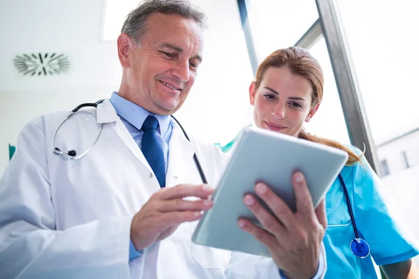 Врач и медсестра обсуждают за цифровым планшетом — стоковое фото