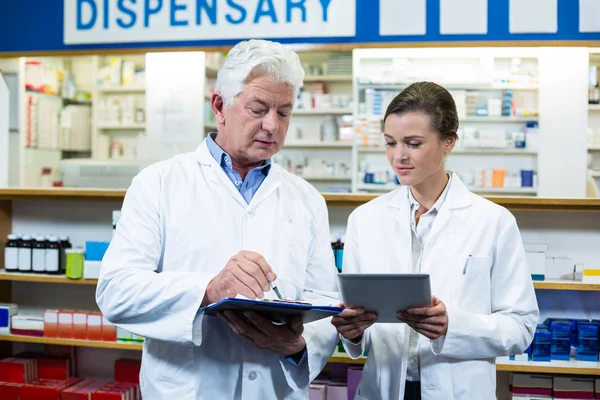 Farmacéuticos discutiendo en tableta y portapapeles — Foto de Stock