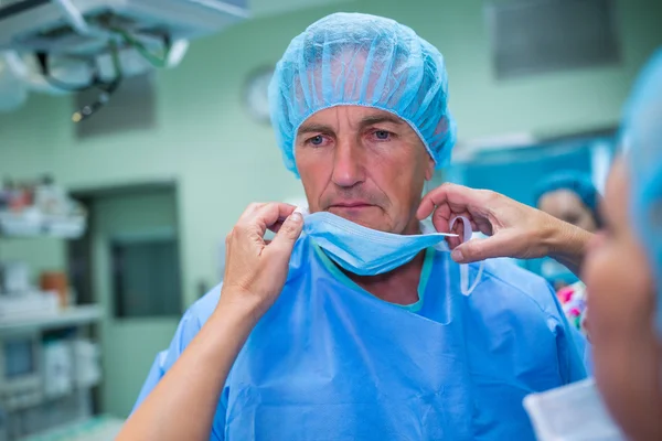 Infirmière aidant un chirurgien à attacher un masque chirurgical — Photo
