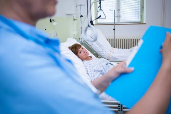 Sjuksköterska företagsakt medan patienten liggande på sängen — Stockfoto