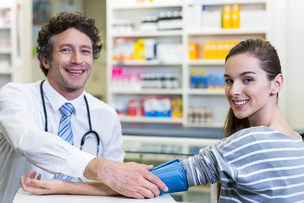 Farmacêutico verificando a pressão arterial do cliente — Fotografia de Stock