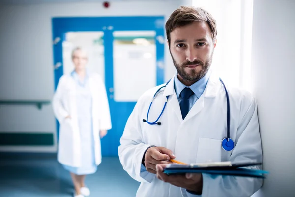 Selbstbewusster Arzt mit Klemmbrett im Krankenhaus — Stockfoto