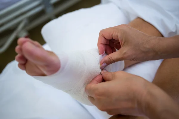 Doctor bandaging patients leg — Stock Photo, Image