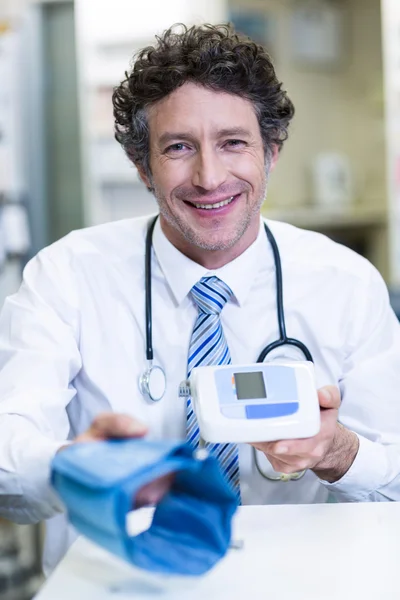 Farmacêutico que detém o monitor de pressão arterial — Fotografia de Stock