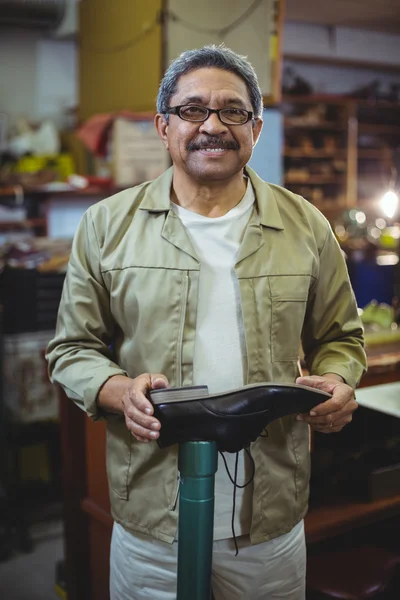 Lachende schoenmaker onderzoeken een schoen — Stockfoto