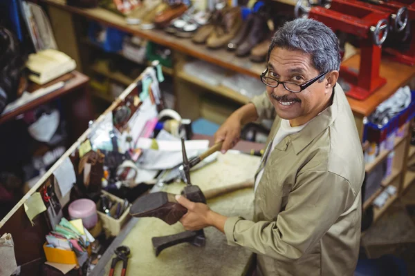 Zapatero sonriente martillando un zapato — Foto de Stock