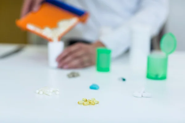 Фармацевт кладет таблетки в контейнер в аптеке — стоковое фото
