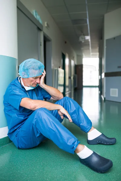 悲伤的外科医生坐在走廊地板上 — 图库照片