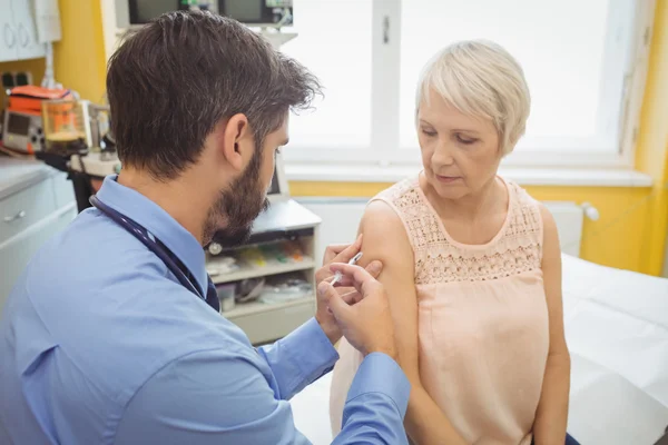 Médico do sexo masculino que administra uma injeção ao doente — Fotografia de Stock