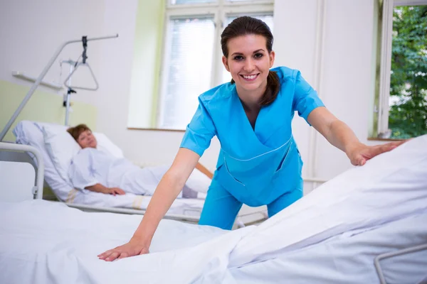 Enfermeira preparando uma cama para um paciente — Fotografia de Stock