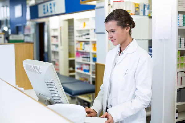 Farmacêutico fazendo registro de prescrição através de computador — Fotografia de Stock