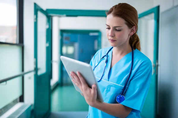 Surgeon using digital tablet in corridor — Stock Photo, Image