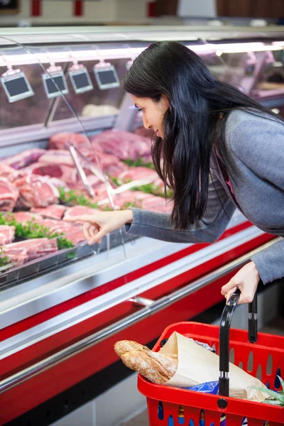 Kvinna som pekar på kött i displayen — Stockfoto