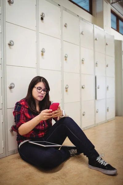 Female student using phone in locker room — Stock Photo, Image