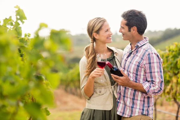 Pareja sosteniendo un vaso y una botella de vino — Foto de Stock