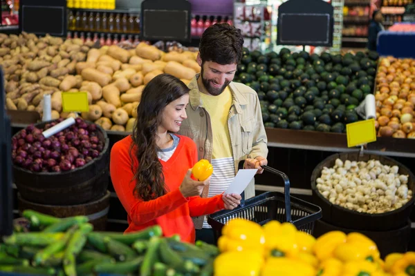 Coppia controllare il loro blocco note durante lo shopping nella sezione biologica — Foto Stock