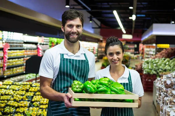 Personal sonriente sosteniendo una caja de pimiento verde en el supermercado —  Fotos de Stock