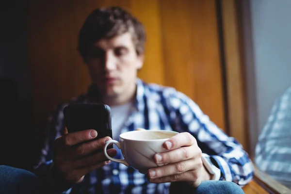 Φοιτητής χρησιμοποιώντας τηλέφωνο πίνοντας καφέ — Φωτογραφία Αρχείου