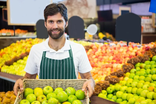 Erkek personel süpermarkette yeşil elma sepeti tutan gülümseyerek — Stok fotoğraf