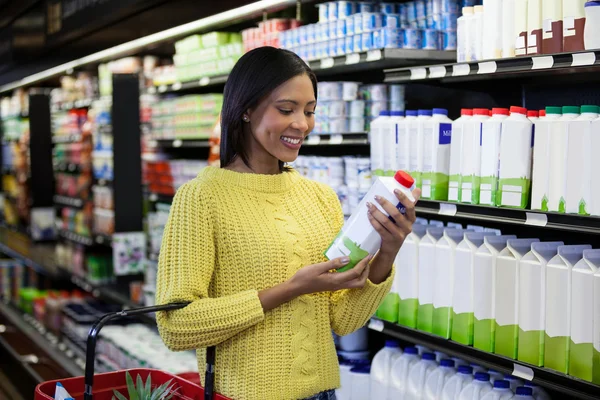 Femme regardant bouteille de lait dans la section des produits laitiers — Photo