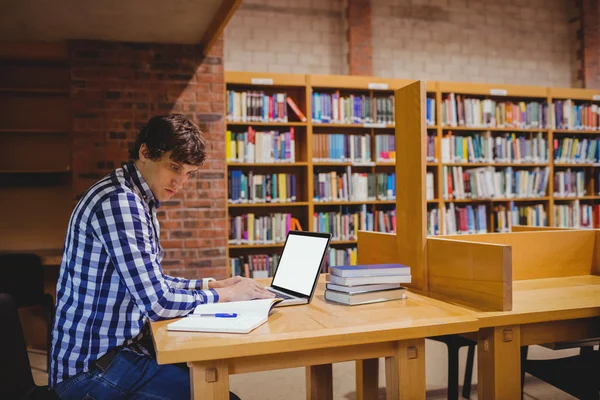 Estudante usando laptop na biblioteca — Fotografia de Stock