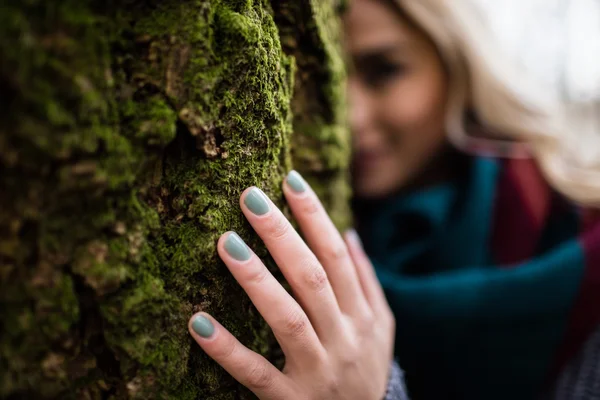 Žena schovává za kmen stromu — Stock fotografie