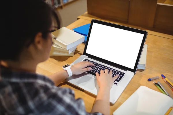 Vrouwelijke student via laptop in bibliotheek — Stockfoto