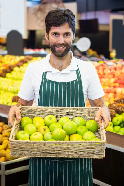 Mosolygó férfi alkalmazottak, tárolás egy kosár zöld alma szupermarketben — Stock Fotó