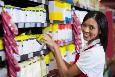 Female staff arranging goods in grocery section clipart